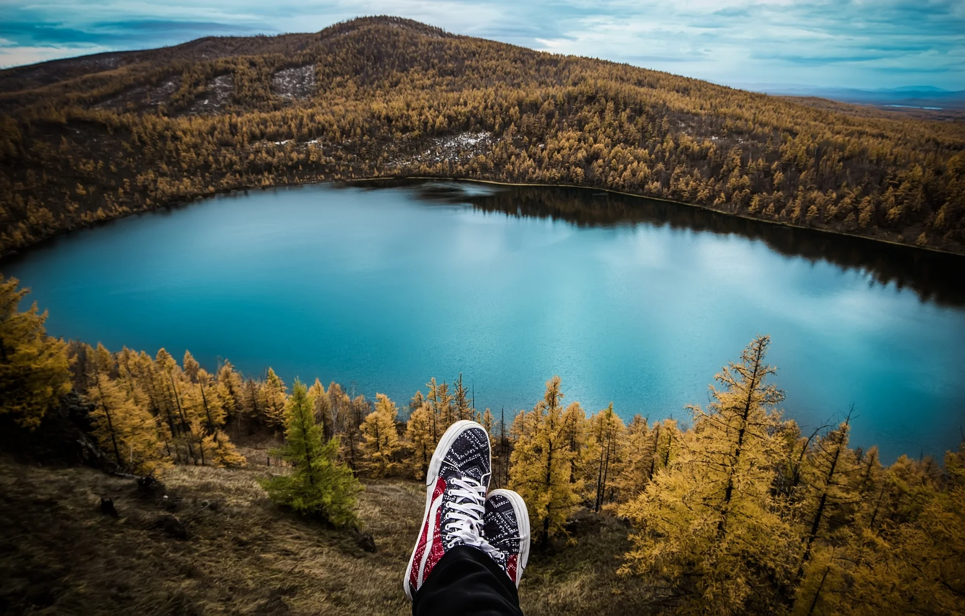 Person's shoes overlooking blue lake