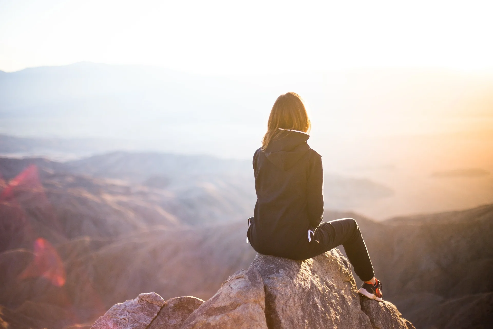 Woman sitting on high peak looking out at the sunrise