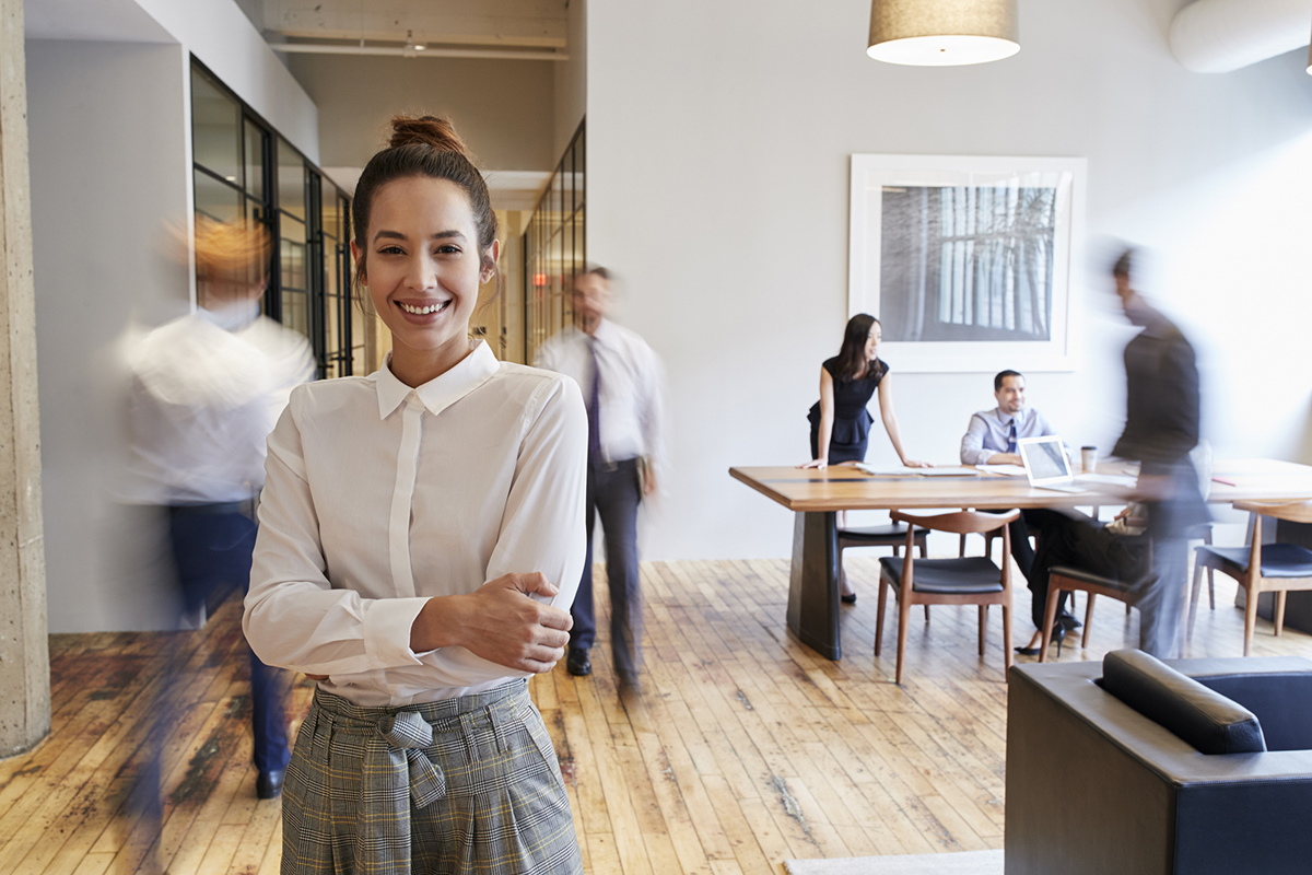 Woman in office with people moving in background