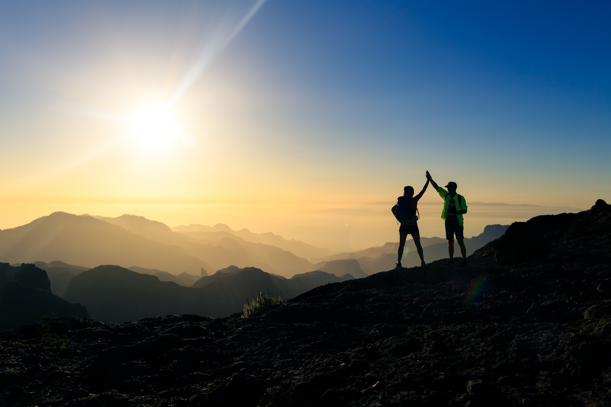 leMan and woman in mountains high five silhouette